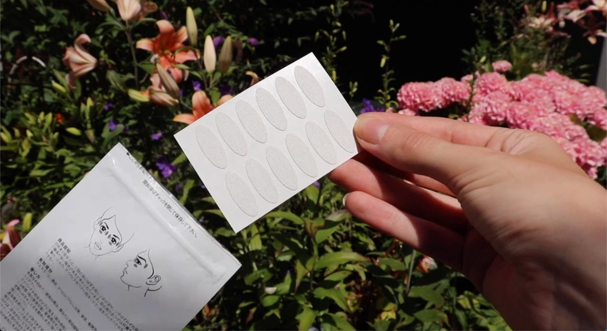A hand holding a sheet of WiseQuest eye patches outdoors, beside the open pouch